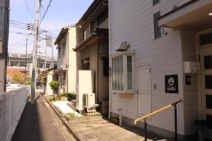 an alleyway next to a white building at Hiroshima Guesthouse HARU in Hiroshima