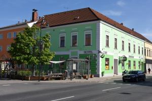 a green and white building on the side of a street at Weinhotel Rieder in Poysdorf