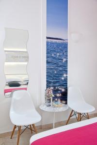 two white chairs in a room with a picture of the ocean at Acqua Vatos Santorini Hotel in Kamari