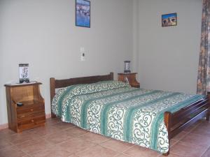 a bedroom with a bed with a green and white blanket at Anastasis Apartments in Trapezaki