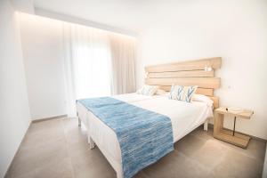 a bedroom with a large white bed with a blue blanket at Seaclub Alcudia Mediterranean Resort in Port d'Alcudia
