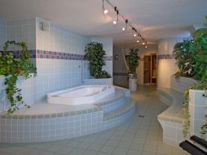 La salle de bains est pourvue de carrelage bleu, d'une baignoire et de plantes. dans l'établissement Hotel Toblacherhof, à Dobbiaco