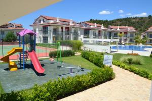 a playground in front of a house with a pool at Korfez Life Apartments in Fethiye