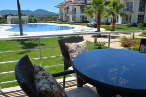 a blue table and chairs on a balcony with a pool at Korfez Life Apartments in Fethiye