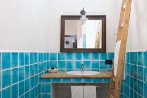 bagno piastrellato blu con lavandino e specchio di Hotel Mercanti di Mare a Santa Marina Salina
