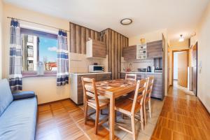 a kitchen and dining room with a wooden table and chairs at Apartamenty Sun & Snow Helska Villa in Hel