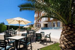 - une table et des chaises avec un parasol à côté de la piscine dans l'établissement Hotel Continental Fano, à Fano