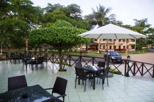 un groupe de tables et de chaises avec un parapluie dans l'établissement Hotel Praia, à São Tomé