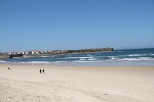 ペニシェにあるBaleal Holidays - Peniche Beach Front Apartmentの海辺の海岸を歩く2人