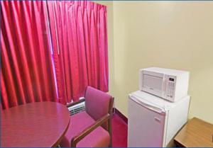 Zimmer mit einem Tisch und einer Mikrowelle auf einem Kühlschrank in der Unterkunft Rumford Motor Inn in Rumford