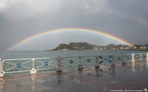 un arco iris sobre un cuerpo de agua con un puente en Marina, en Ribadesella