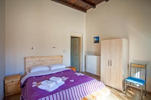 sypialnia z fioletowym łóżkiem i ręcznikami w obiekcie Ihnilatis w mieście Kerkíni