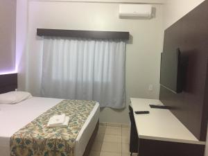 a bedroom with a bed and a desk and a television at Hotel Notre Dame in Luis Eduardo Magalhaes