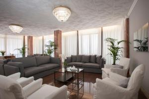 ein Wohnzimmer mit Sofas, Tischen und Fenstern in der Unterkunft Hotel Imperial Palace in Lido di Jesolo
