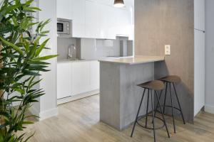 eine Küche mit weißen Schränken und einer Theke mit Stühlen in der Unterkunft Marina Suite by FeelFree Rentals in San Sebastián