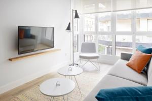 ein Wohnzimmer mit einem Sofa und einem TV an der Wand in der Unterkunft Marina Suite by FeelFree Rentals in San Sebastián