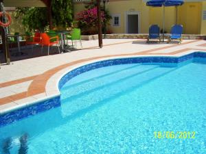 una piscina azul con sillas y sombrilla en Apelia Residence, en Agia Marina de Nea Kydonia