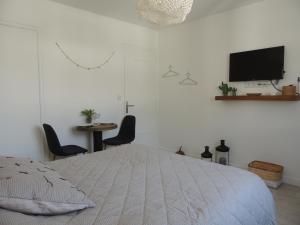 a white bedroom with a bed and a tv on the wall at Le "Wood" in Annecy