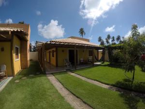 a small yellow house with a green yard at Bangalô Patacho in Pôrto de Pedras