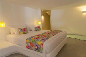 a white bedroom with a bed with a colorful blanket at Ayoba Santorini in Imerovigli