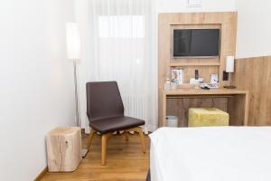 a bedroom with a bed and a chair and a television at Hotel Goldenes Rad in Ulm