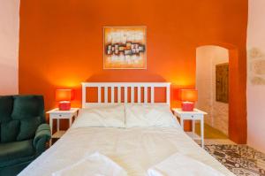 ein Schlafzimmer mit einer orangefarbenen Wand mit einem Bett und einem Stuhl in der Unterkunft Il-Wileġ Bed & Breakfast in Qala