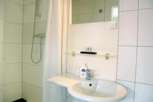 y baño blanco con lavabo y ducha. en Ensche-Day Inn, en Enschede