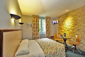 ein Schlafzimmer mit einem Bett und einer Steinmauer in der Unterkunft Hôtel des Récollets in Sarlat-la-Canéda