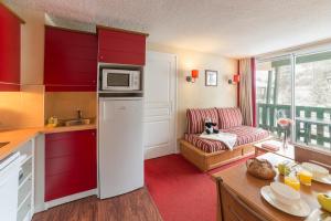 uma cozinha com armários vermelhos e uma sala de estar em Résidence Pierre & Vacances Pyrenees 2000 Le Séquoia em Bolquère - Pyrénées 2000