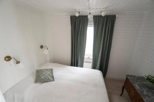 um quarto com uma cama branca e uma janela em Anfasteröd Gårdsvik - Badstugorna em Ljungskile