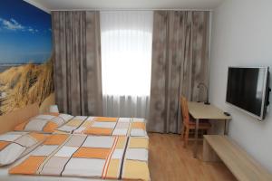 a bedroom with a bed and a desk and a television at Appartementhaus Anna in Linz