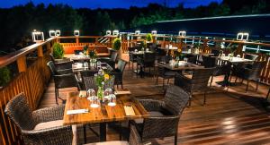a restaurant with tables and chairs on a deck at Akademia Kuraszków in Kuraszków