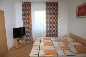 a bedroom with four beds and a tv and curtains at Appartementhaus Anna in Linz