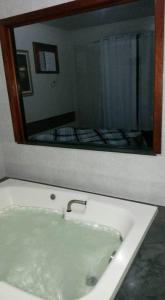 a white bath tub with a large mirror above it at Pousada Beija Flor in Cambuci