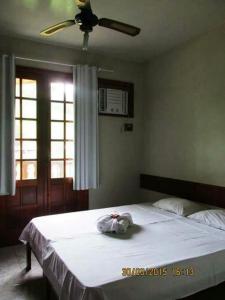 Schlafzimmer mit einem weißen Bett und einem Deckenventilator in der Unterkunft Pousada Beija Flor in Cambuci