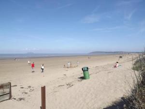 a group of people walking on a beach at Hill View Apartment in Brean