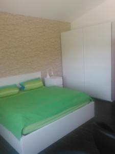 ein Schlafzimmer mit einem weißen Bett mit grüner Bettwäsche in der Unterkunft Ferienwohnung zum Kletterturm in Kaufbeuren