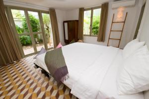 a bedroom with a large white bed and windows at Bambu Hotel in Battambang