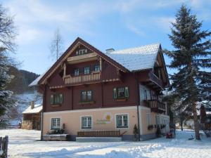 a large wooden house with snow on the ground at Renovated holiday home in the mountains in Pruggern