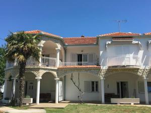 ein großes weißes Haus mit einer Palme in der Unterkunft Apartments Roko in Turanj