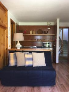 un divano blu in soggiorno con cucina di Maison De Pitti a La Thuile