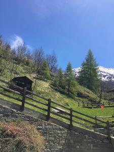 a wooden fence in front of a hill with a house at Maison De Pitti in La Thuile