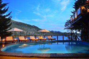 a large swimming pool with chairs and umbrellas at Dos Bahias Lake Resort in Villa La Angostura
