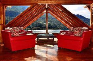 two red chairs in a room with a large window at Dos Bahias Lake Resort in Villa La Angostura