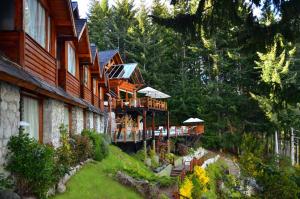 a building on a hill next to a forest at Dos Bahias Lake Resort in Villa La Angostura
