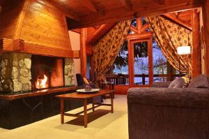 a living room with a fireplace and a couch and a table at Dos Bahias Lake Resort in Villa La Angostura