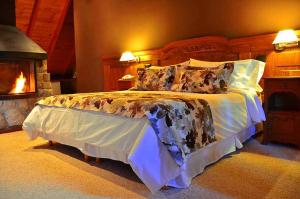 a bedroom with a large bed with a fireplace at Dos Bahias Lake Resort in Villa La Angostura