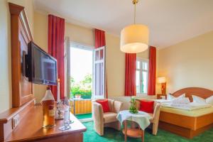 バート・ハルツブルクにあるHotel Victoriaのベッドとリビングルームが備わるホテルルームです。
