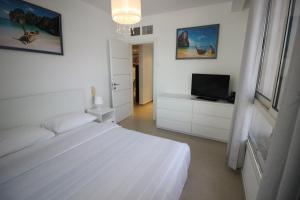 a white bedroom with a bed and a television at Sunset apartment's Residence du Golf in Eilat