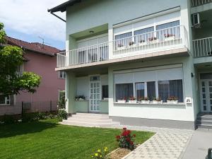 una casa con balcones y flores en un patio en Apartment Marija en Slavonski Brod